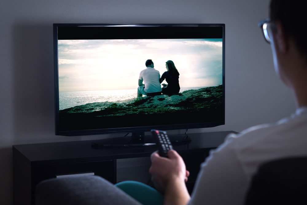 Personne regardant un écran de télévision avec un couple qui regarde la mer
